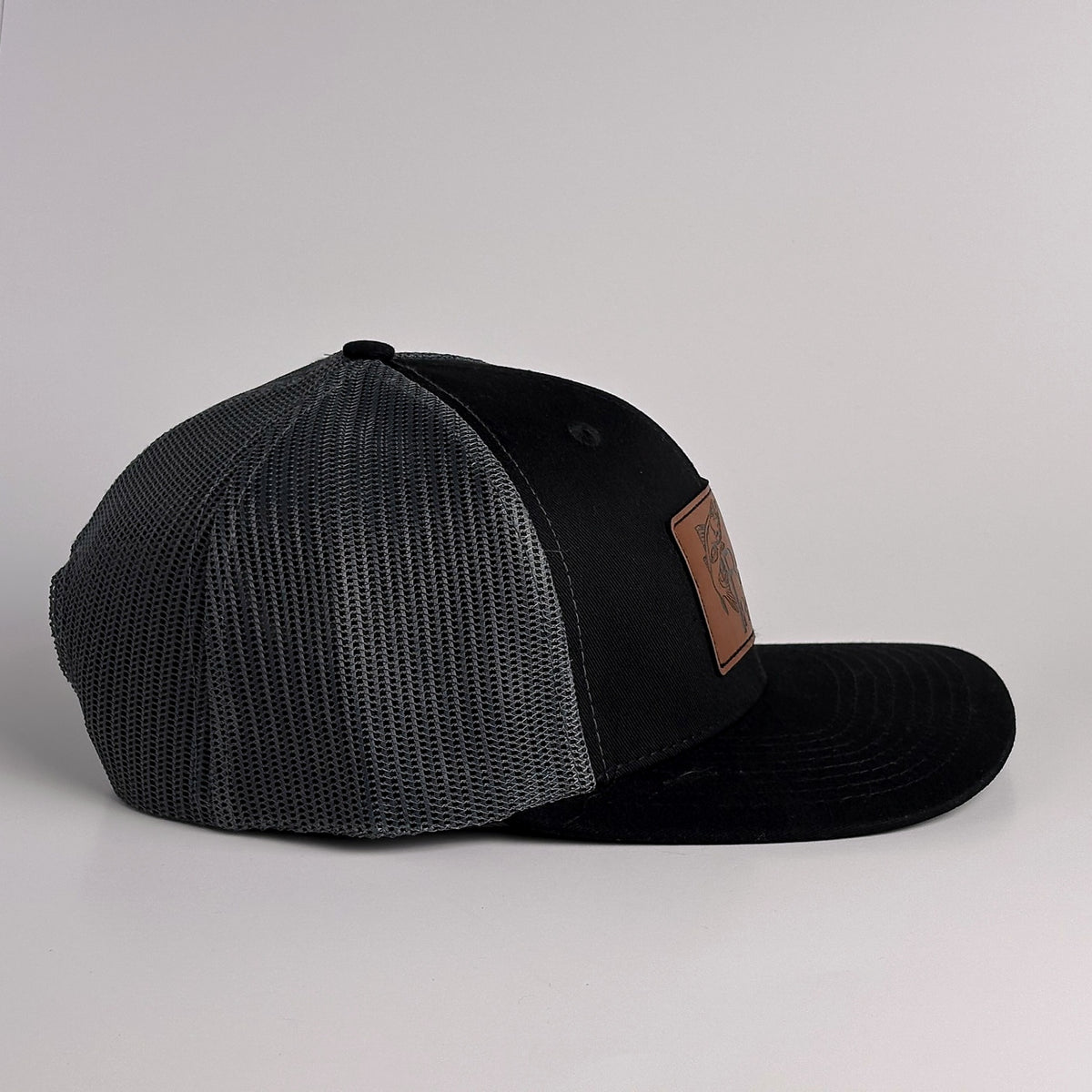 Black and charcoal grey mesh trucker hat with snapback side view