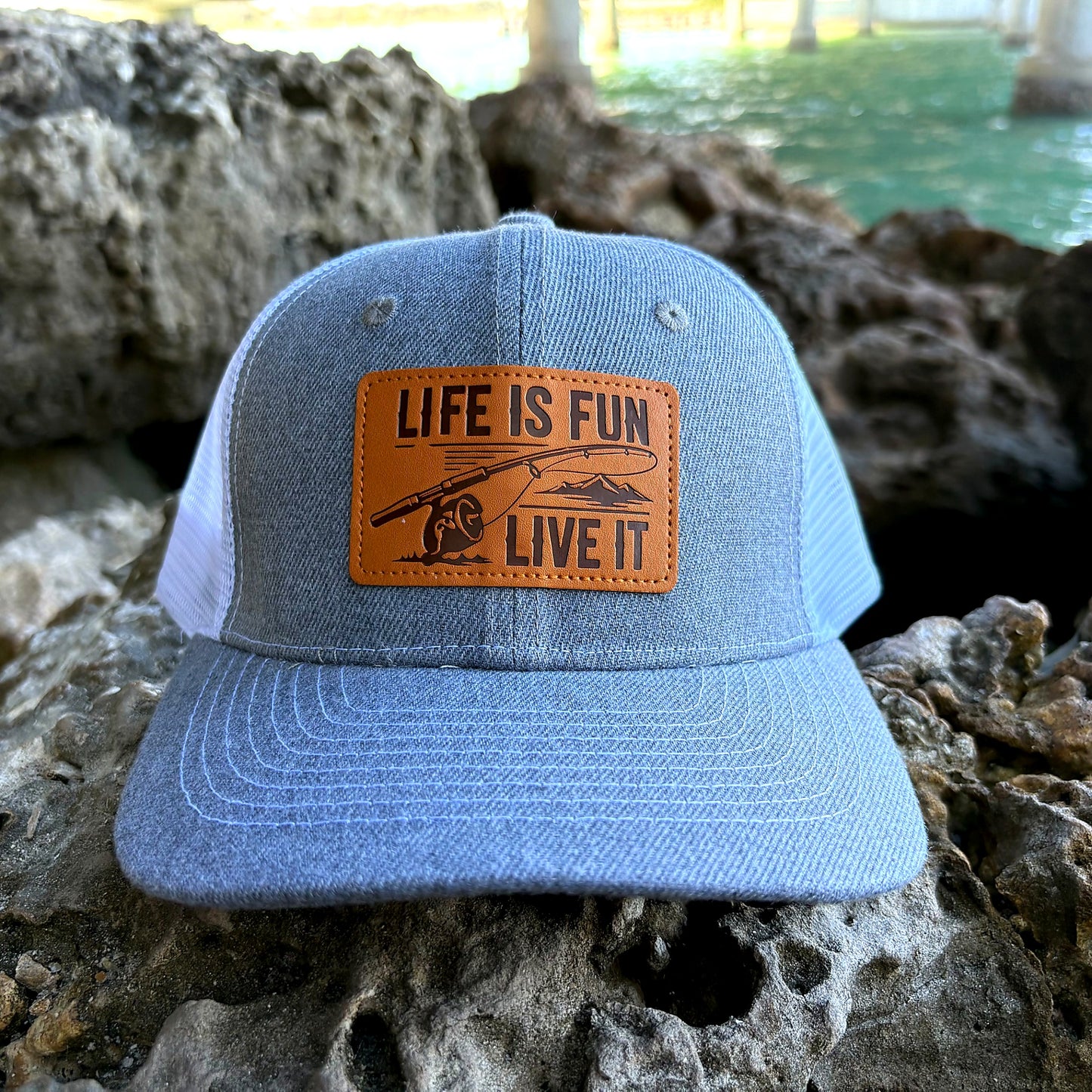 Life Is Fun Live It fishing hat on rock near water lifestyle shot
