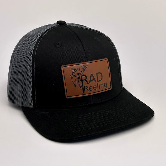 Black and charcoal grey mesh trucker hat with Rad Reeling leather patch front view